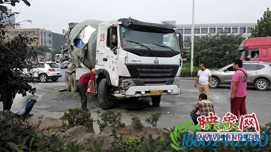被吊起来的水泥罐车，地下还洒有水泥，车身右侧受伤较重。