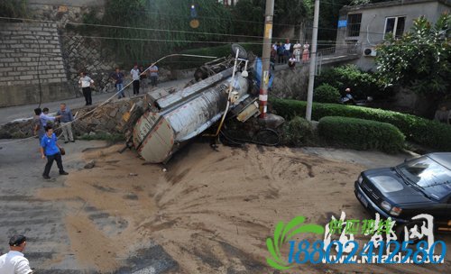 翻在路边的油罐车，等待吊车救援。洒满废油的路面已铺上沙子，以防过往车辆打滑
