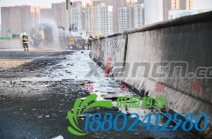 消防队员给扶正的罐车喷水降温,泄漏的原油沿着高架桥流淌